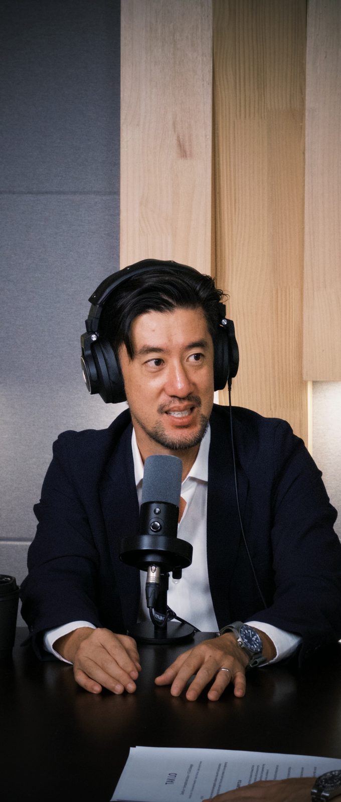 Tak Lo at the mic, turned toward Thomas, mid-sentence on the gap between US Armageddon framing and China productivity framing of AI