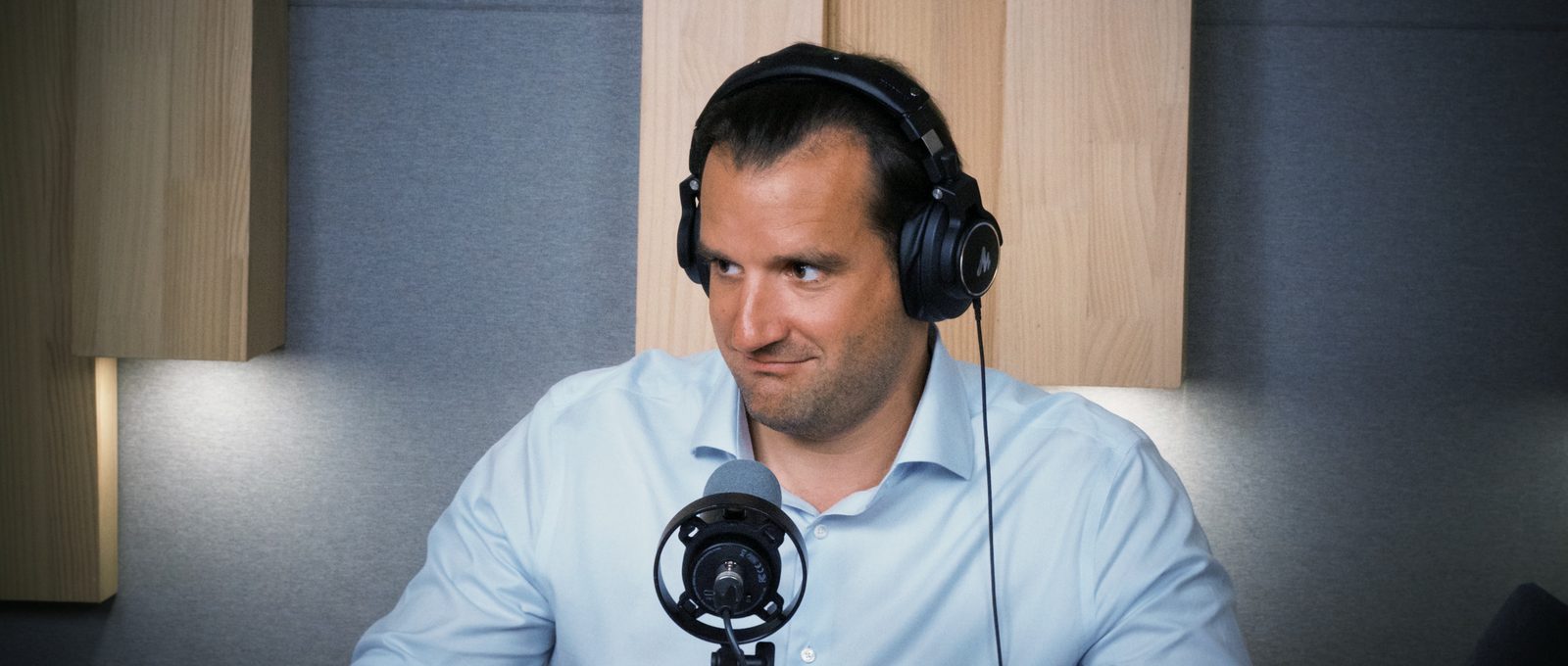 Rafael Ratzel with headphones turned toward Thomas, a half-smile mid-sentence, the moment he frames the Saudi LP in Shenzhen reading Chinese chip valuations against Silicon Valley multiples