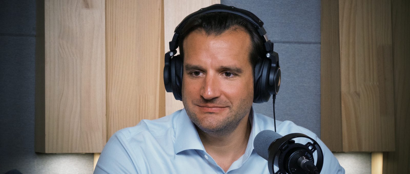 Rafael Ratzel smiling at the mic with studio headphones on, the moment he refuses the "auswandern" emigrant label after eighteen years in China